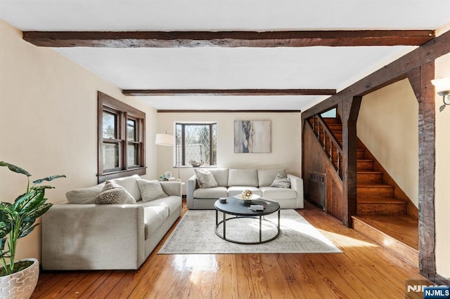 living area featuring beam ceiling, stairway, and hardwood / wood-style flooring