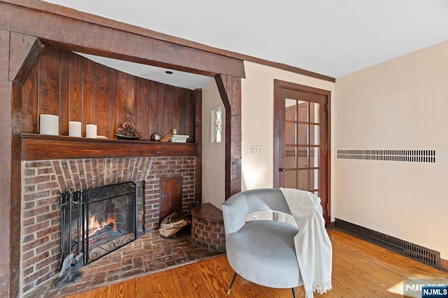 sitting room featuring a brick fireplace, baseboards, and wood finished floors