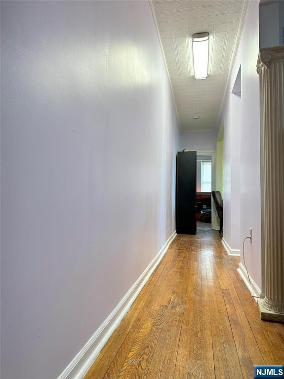 corridor featuring ornamental molding, baseboards, and hardwood / wood-style flooring