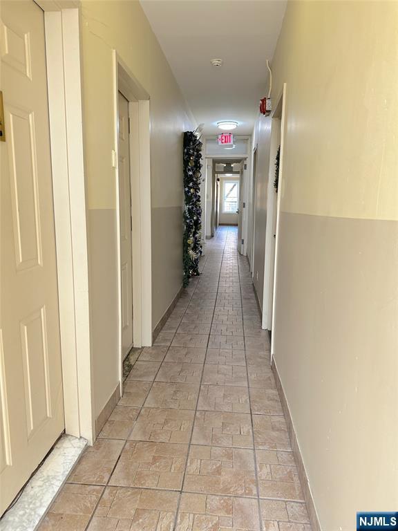 corridor featuring brick floor and baseboards