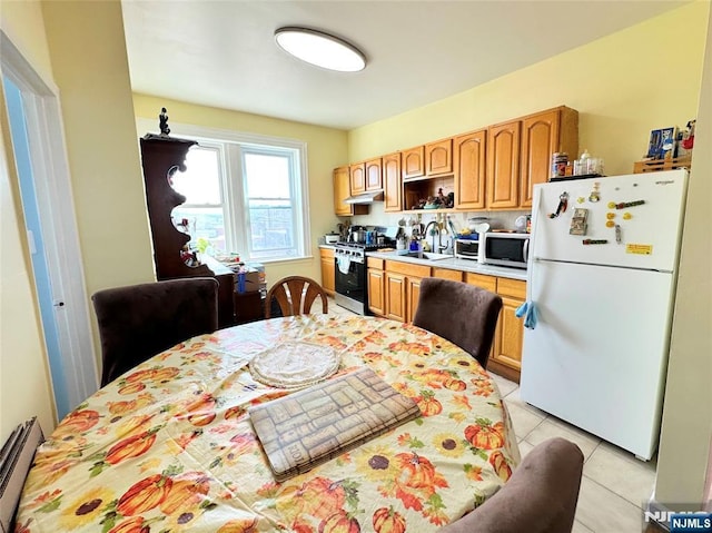 kitchen featuring light tile patterned floors, a baseboard heating unit, a sink, light countertops, and appliances with stainless steel finishes