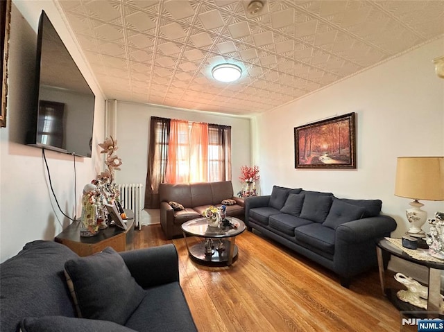 living area with an ornate ceiling, radiator, and wood finished floors