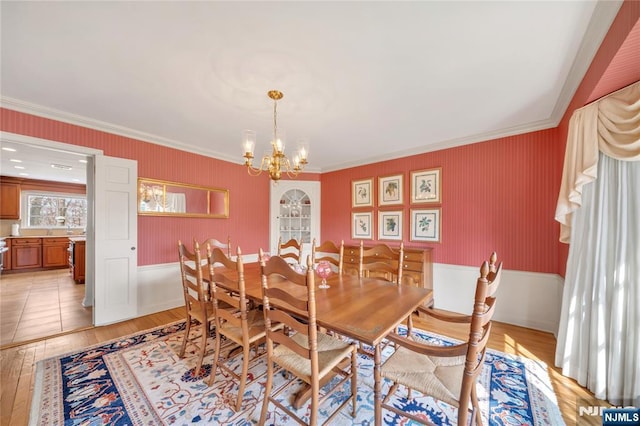 dining room with wallpapered walls, ornamental molding, light wood finished floors, and an inviting chandelier