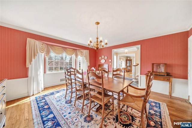 dining space featuring light wood-style floors, ornamental molding, and an inviting chandelier