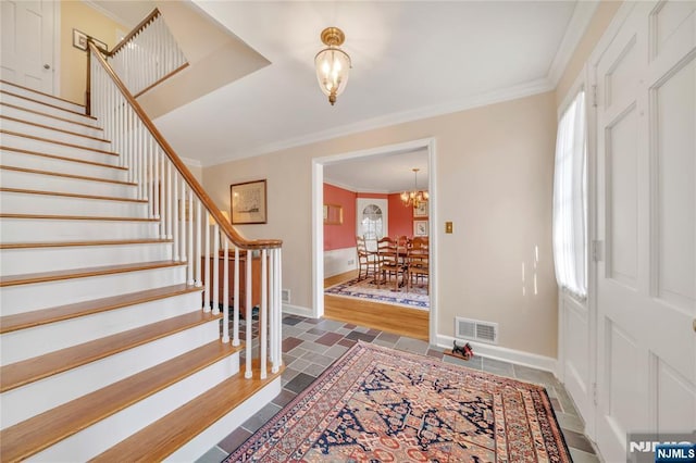 foyer featuring ornamental molding, stairway, baseboards, and an inviting chandelier