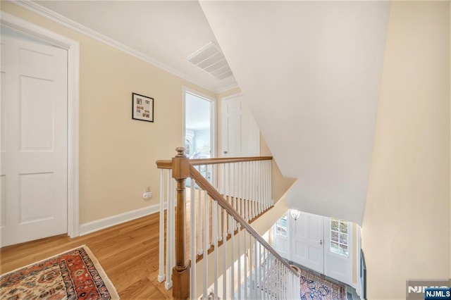 stairs with visible vents, baseboards, wood finished floors, and ornamental molding