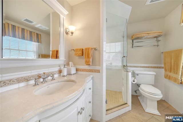 bathroom with a wainscoted wall, tile patterned flooring, and tile walls