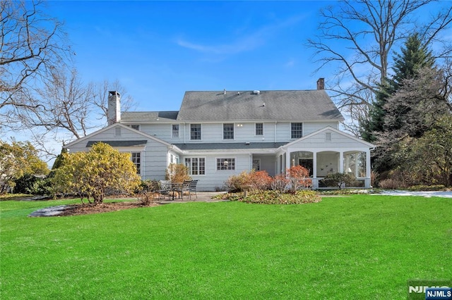 rear view of house featuring a chimney, a patio, and a yard