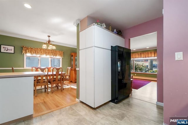 kitchen featuring a chandelier, a healthy amount of sunlight, baseboard heating, and white cabinets