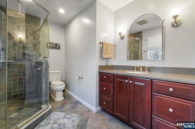 bathroom with toilet, vanity, visible vents, baseboards, and a stall shower