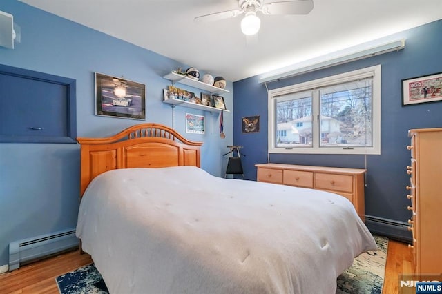 bedroom featuring a baseboard heating unit, a baseboard radiator, wood finished floors, and a ceiling fan