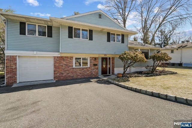 view of front of house with brick siding, a front lawn, an attached garage, and aphalt driveway