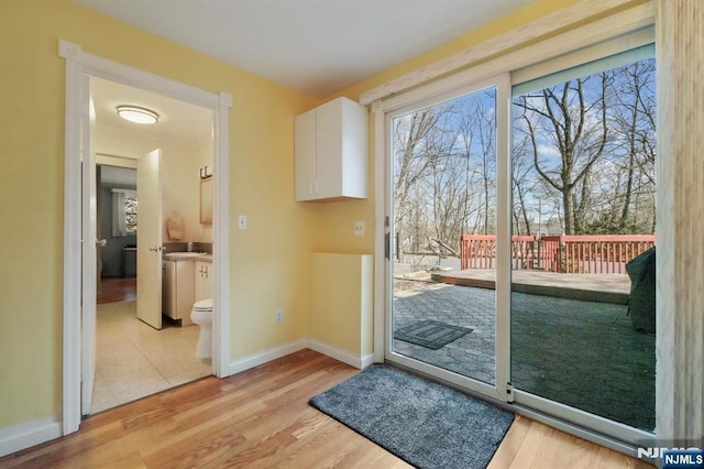 doorway with light wood-type flooring and baseboards