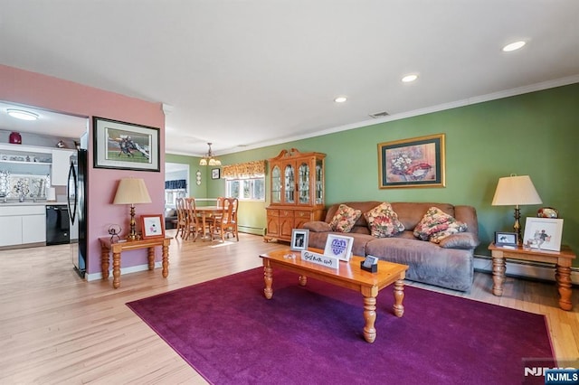 living area with a baseboard heating unit, light wood-type flooring, a baseboard radiator, and crown molding