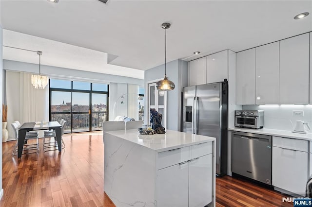 kitchen with a kitchen island, modern cabinets, appliances with stainless steel finishes, decorative light fixtures, and white cabinetry