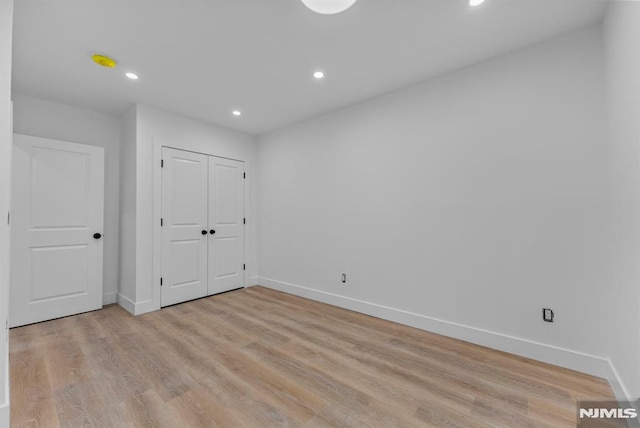 unfurnished bedroom featuring recessed lighting, a closet, light wood-style flooring, and baseboards