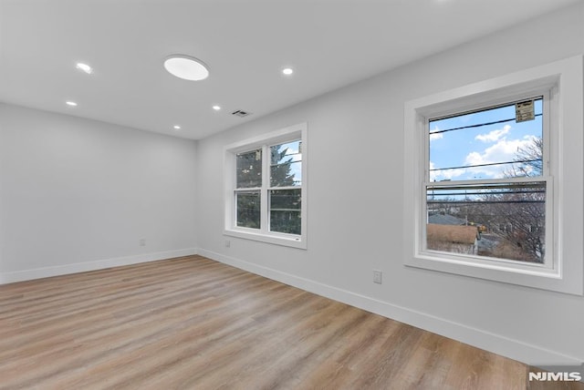 empty room with light wood-style floors, baseboards, and recessed lighting