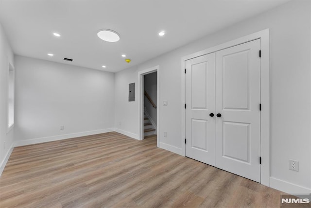 interior space with light wood finished floors, electric panel, baseboards, stairs, and recessed lighting