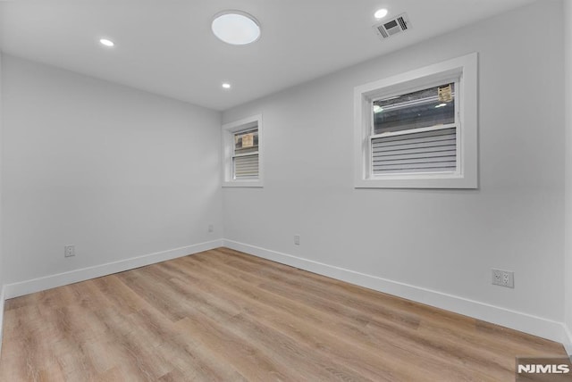 spare room with recessed lighting, wood finished floors, visible vents, and baseboards