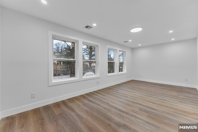 unfurnished room featuring recessed lighting, wood finished floors, visible vents, and baseboards