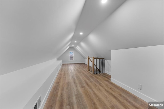 additional living space with recessed lighting, wood finished floors, visible vents, baseboards, and vaulted ceiling