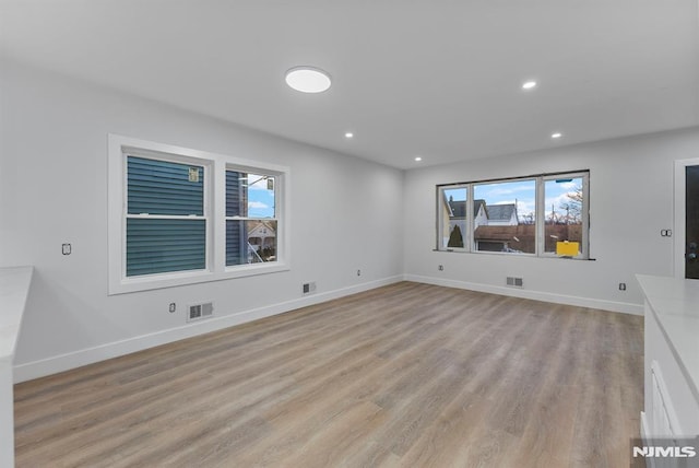 interior space with light wood finished floors, baseboards, and visible vents