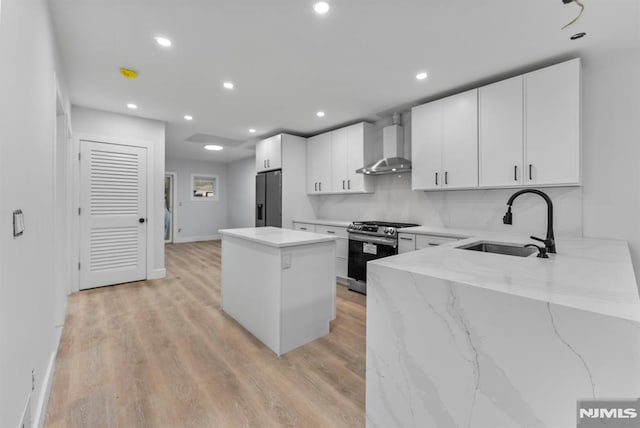 kitchen featuring a center island, black fridge with ice dispenser, gas stove, a sink, and wall chimney range hood