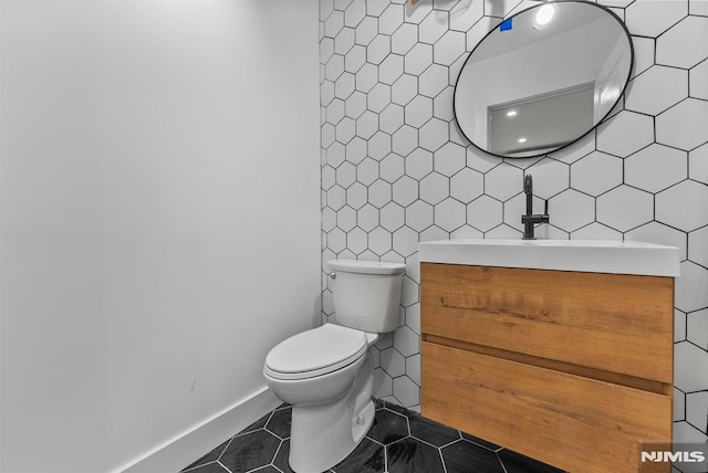 bathroom with toilet, vanity, tile walls, and tile patterned floors