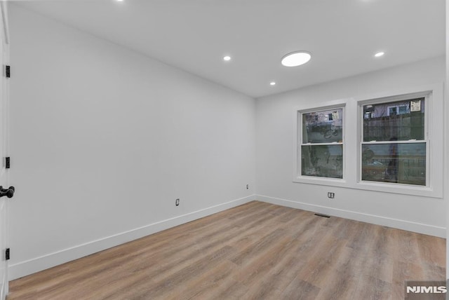 spare room featuring light wood-style flooring, visible vents, baseboards, and recessed lighting