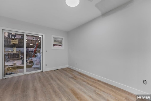 spare room featuring baseboards and wood finished floors