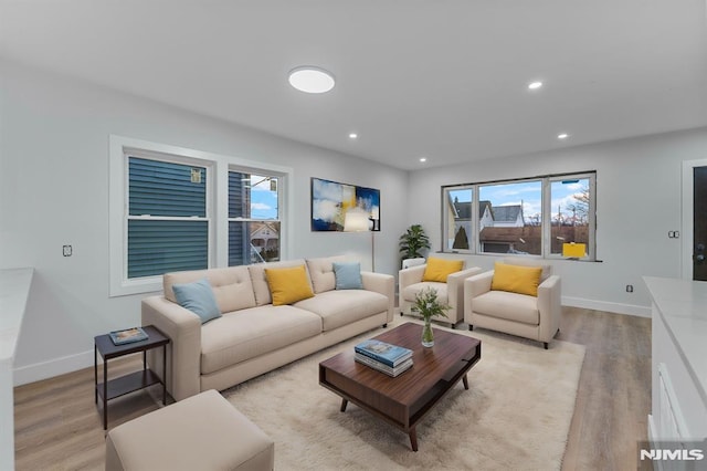 living room featuring light wood-style flooring, baseboards, and recessed lighting