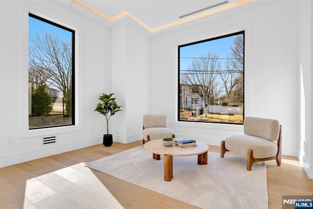 living area with visible vents, baseboards, and light wood finished floors