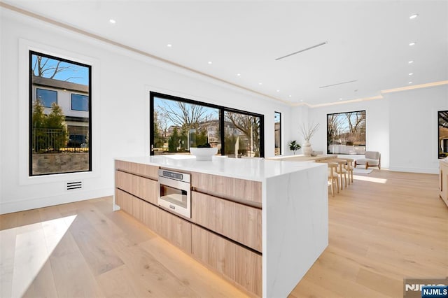 kitchen with oven, modern cabinets, light wood-style flooring, and light brown cabinetry