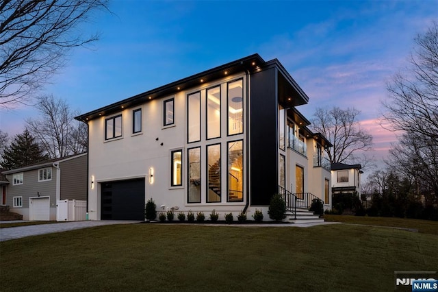 exterior space featuring a garage, stucco siding, driveway, and a yard