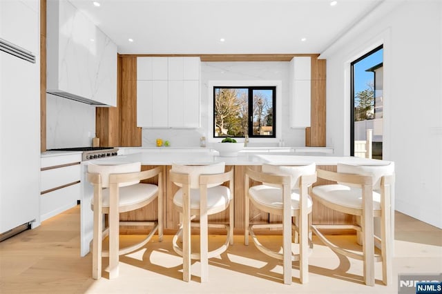 kitchen featuring a breakfast bar, white cabinetry, light countertops, and modern cabinets