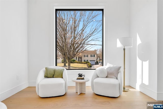 sitting room with a wealth of natural light, baseboards, and wood finished floors