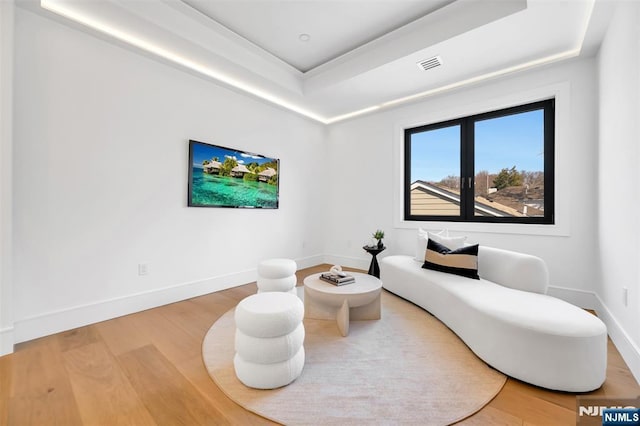 sitting room featuring visible vents, baseboards, a tray ceiling, and wood finished floors