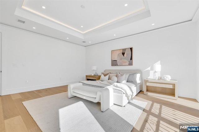 bedroom featuring recessed lighting, light wood-style flooring, a raised ceiling, and baseboards