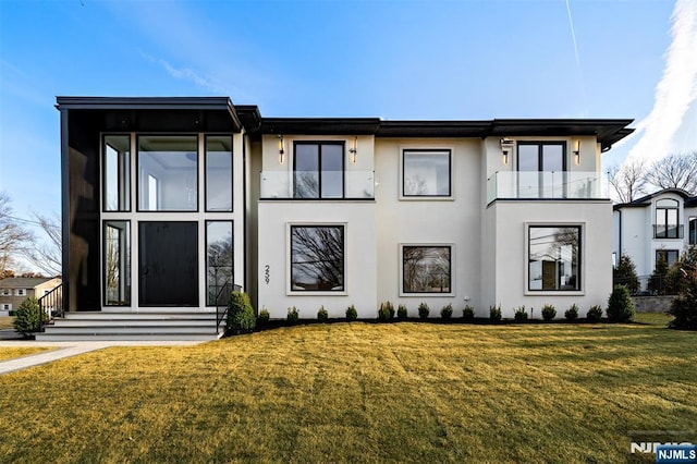 view of front of property with stucco siding, a balcony, a front yard, and entry steps