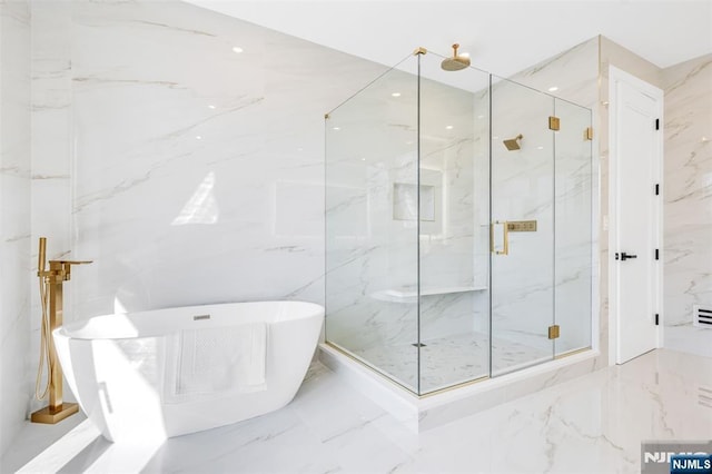 full bathroom with a marble finish shower, a soaking tub, marble finish floor, and stone wall