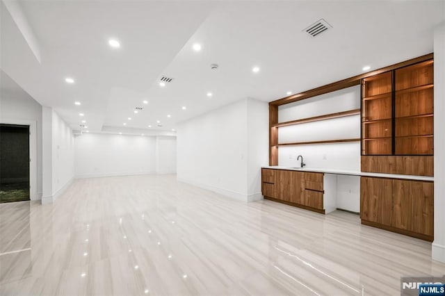 unfurnished living room featuring a sink, visible vents, baseboards, and recessed lighting