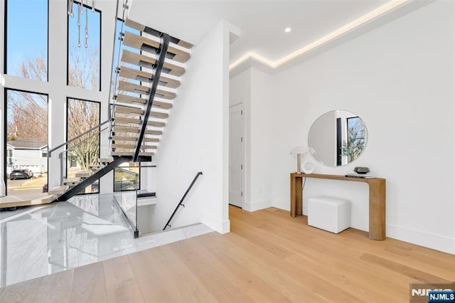 stairway with a high ceiling, wood finished floors, and baseboards