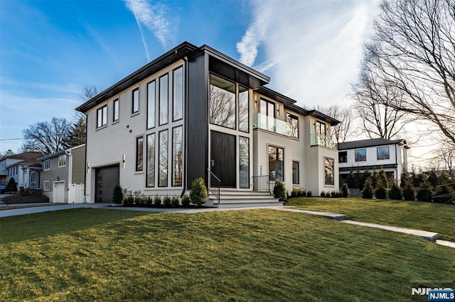 view of front of property with stucco siding, an attached garage, driveway, and a front yard