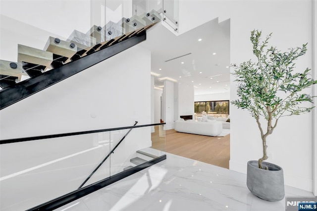 stairway with marble finish floor and a high ceiling