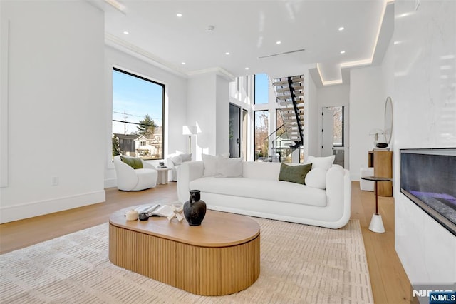 living area with a glass covered fireplace, baseboards, wood finished floors, and recessed lighting