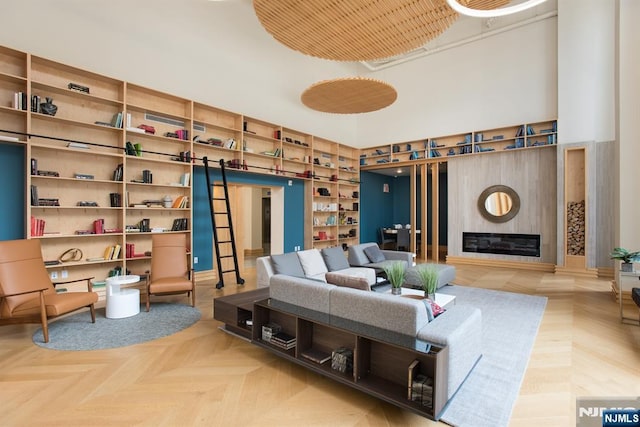 interior space with built in shelves, a glass covered fireplace, and a high ceiling