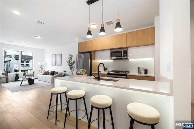 kitchen featuring light countertops, visible vents, appliances with stainless steel finishes, open floor plan, and a sink