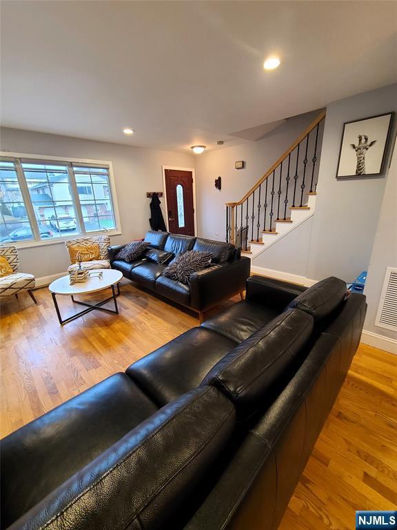 living room with recessed lighting, visible vents, light wood finished floors, and stairs