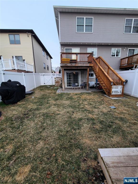 back of house with a fenced backyard, a lawn, and stairs