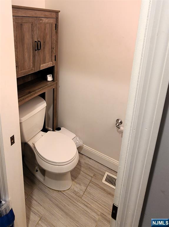 bathroom with baseboards, visible vents, and toilet